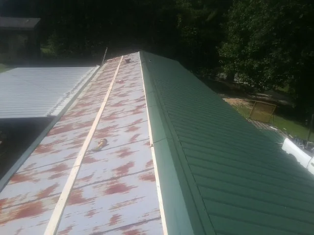 Old rusted panels beside newly installed green metal roofing — Wind Damage Roof Repair by Roofing Brothers in Cleveland
