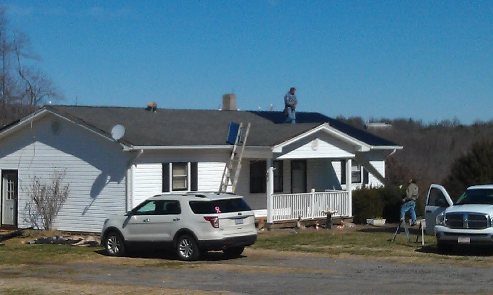 Roofers stripping shingles from a white ranch house roof in Cleveland